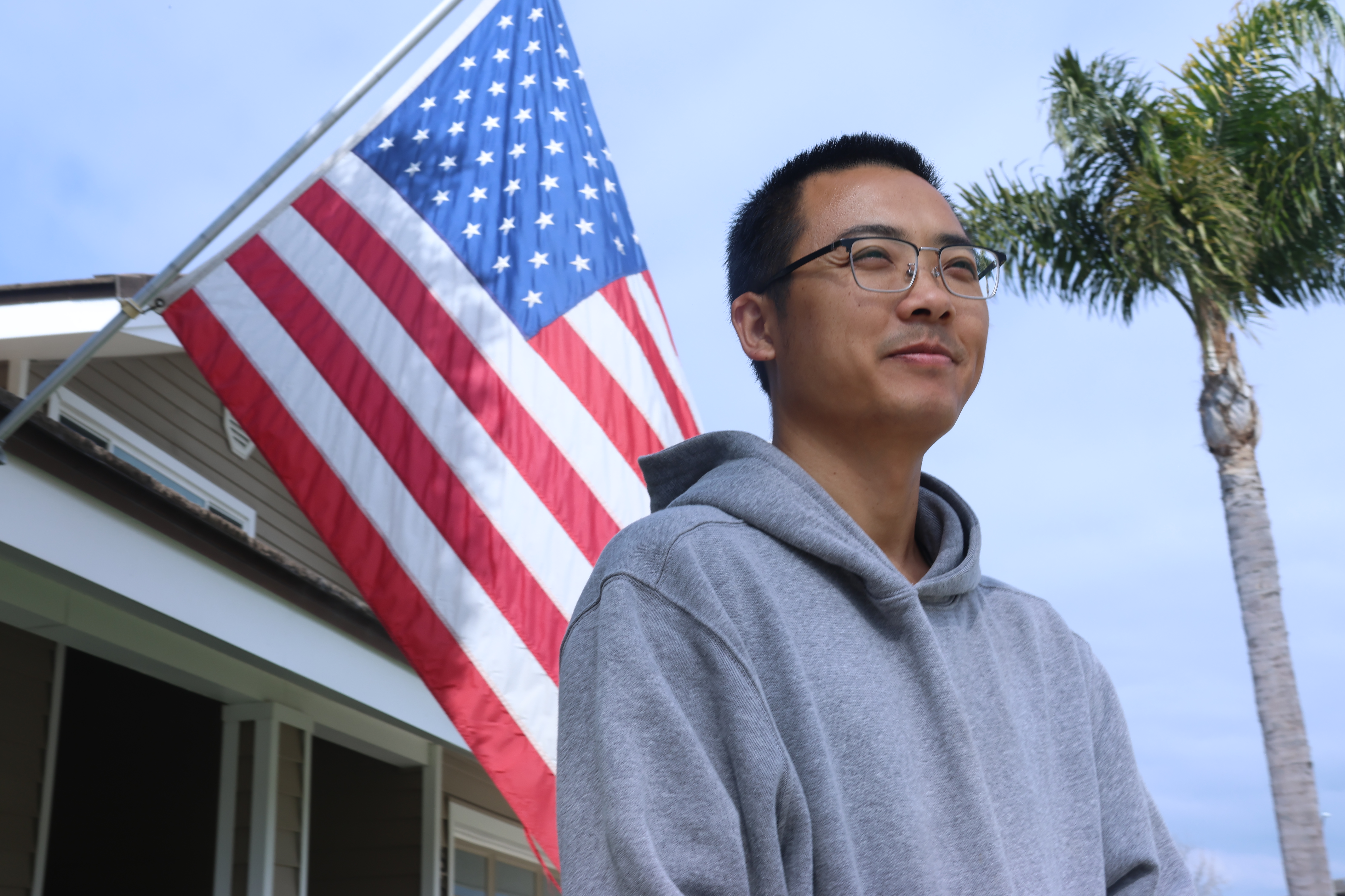 While making deliveries, Jiang pauses outside a home flying the American flag