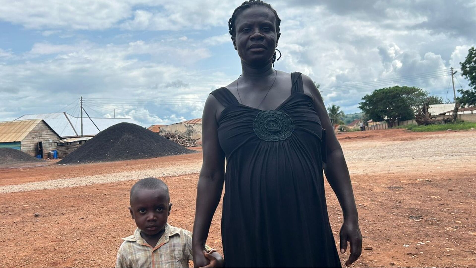 Pregnant woman in black dress poses with son